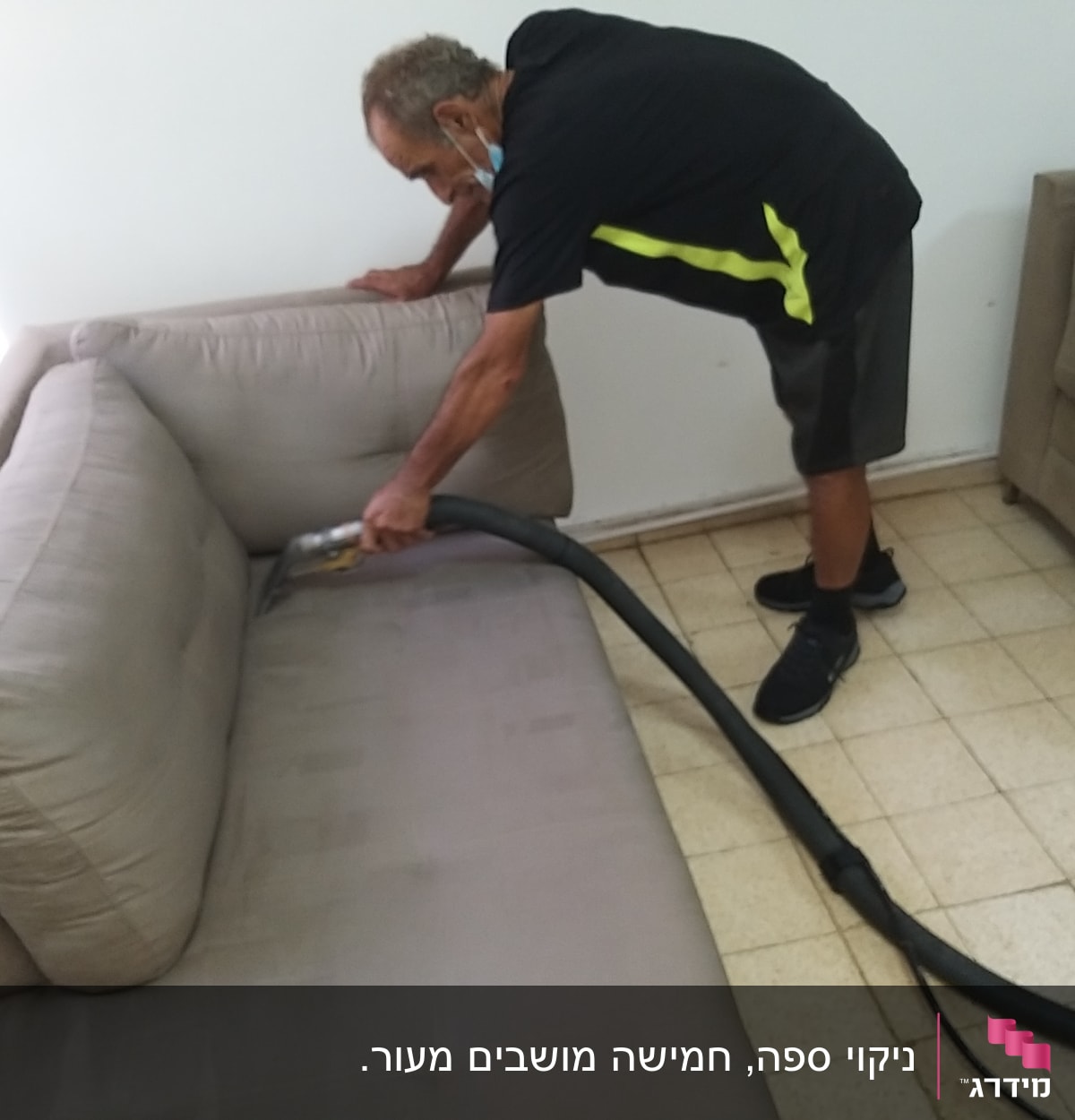 אדם מנקה ספה עם שואב אבק